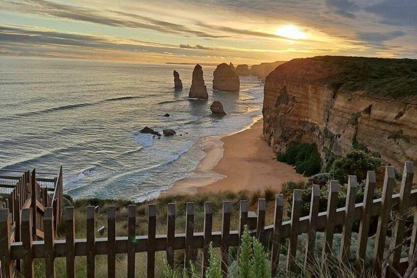 A coastal landscape with cliffs, a sandy beach, and a wooden fence. 1