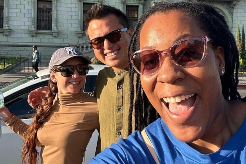 Tres personas de pie frente a un edificio con columnas. 3