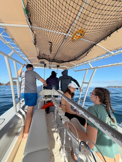 A group of people on a boat with a netted canopy overhead. 4