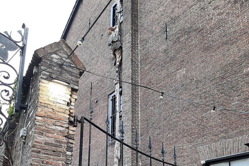 A brick building with a stone tower, a metal sign, and a street lamp. 3