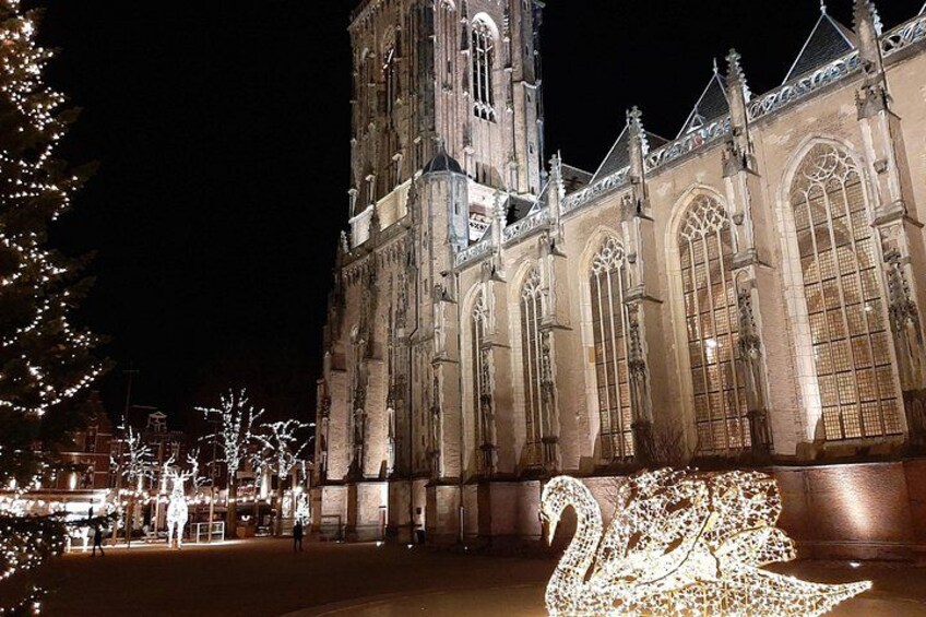 A historic building with large arched windows and a tall tower, illuminated at night. 2