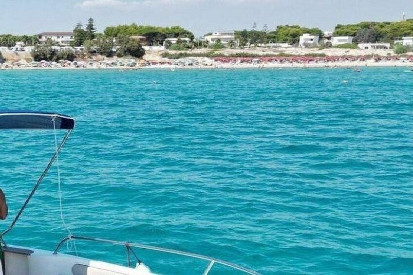 Un bateau sur une eau turquoise, avec une plage et des bâtiments en arrière-plan. 3