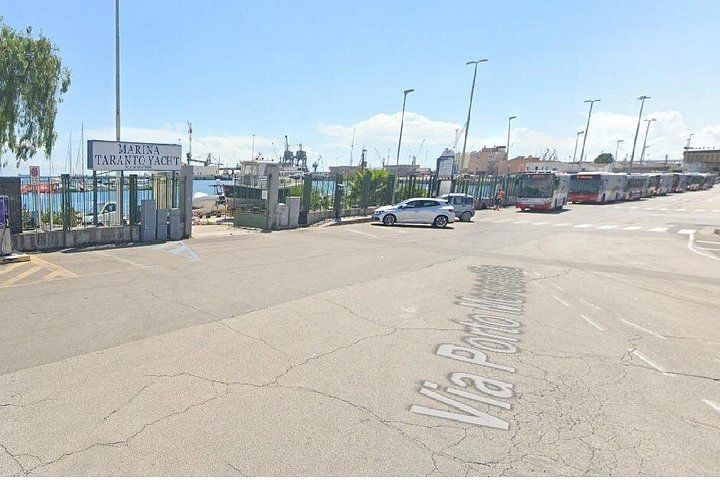Un port de plaisance avec des bateaux amarrés et une enseigne indiquant « Marina Taranto Yacht ». 2