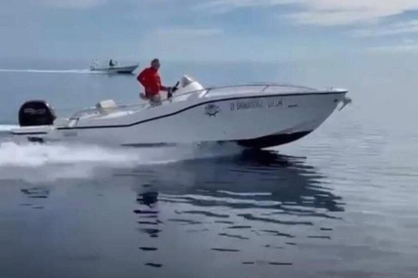 Un bateau à moteur filant sur une eau calme, avec une personne portant un t-shirt rouge. 5