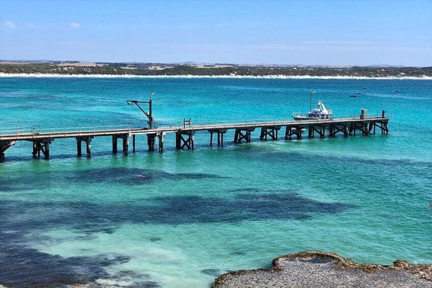 A pier extending into turquoise water with a boat docked at the end. 2