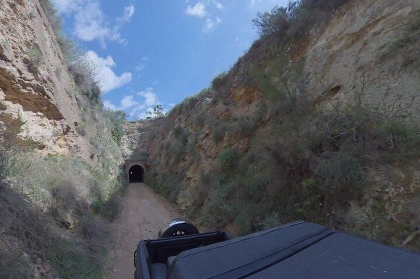 A narrow canyon road with a tunnel entrance. 1