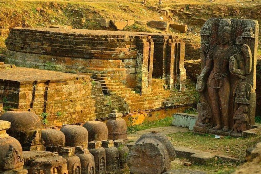 Ancient ruins with stone structures and a large statue. 1