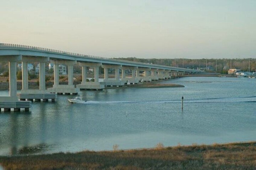 A long bridge over a river with a boat in the water. 1