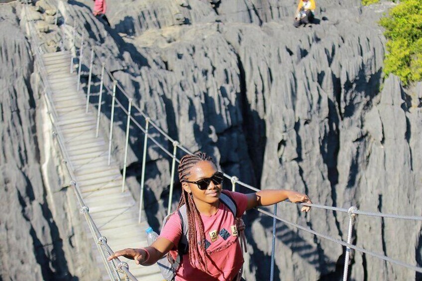 A person standing on a rope bridge over a rocky cliff. 2