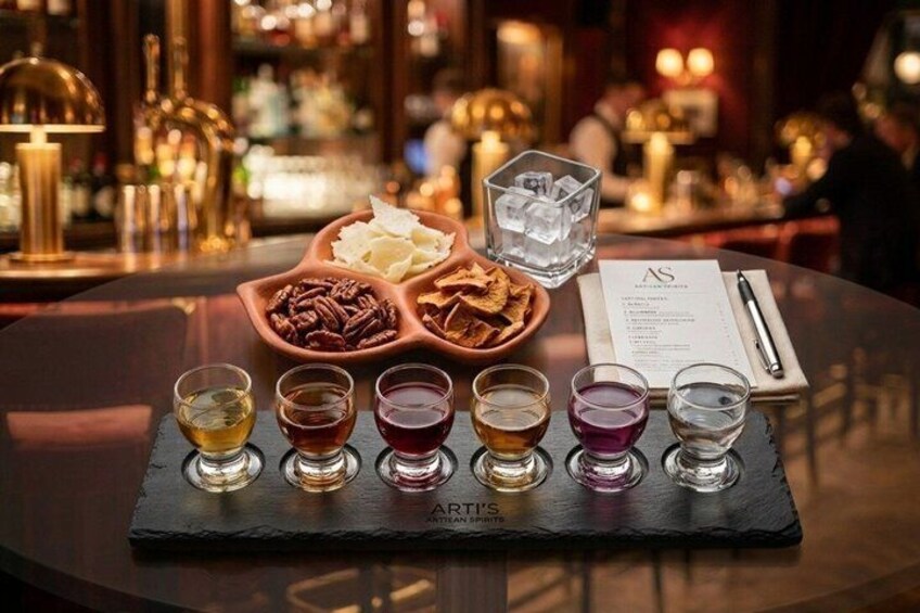 A bar setting with a slate serving tray holding shot glasses and a bowl of nuts. 3