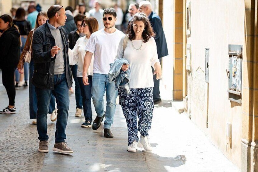 A crowded street with people walking, buildings, and a narrow alleyway. 5