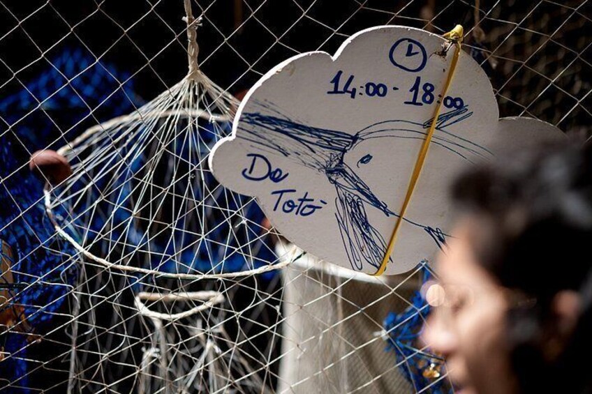 A birdcage with a sign indicating the time '14:00-18:00' and the word 'De Tot'. 2