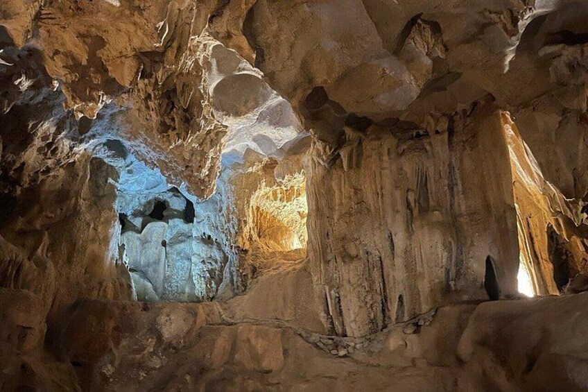 A cave with stalactites and stalagmites, natural rock formations, and a narrow passageway. 2