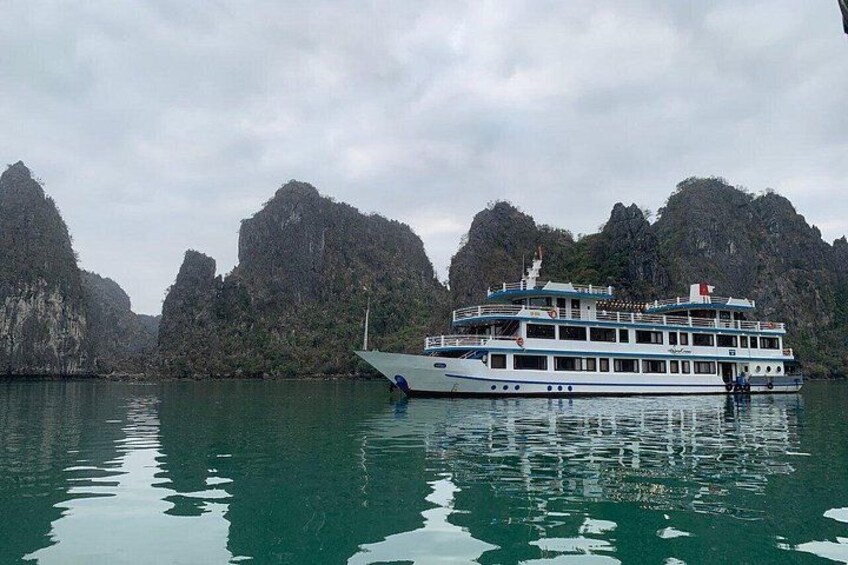A large white boat with multiple decks on calm water, surrounded by steep, rocky cliffs. 4