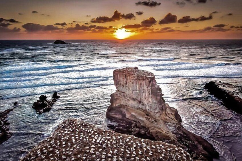 A coastal landscape with a prominent rock formation, ocean waves, and a sunset. 3