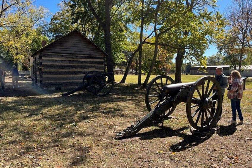 A historical cannon, a wooden cabin, and a person standing by the cannon. 1