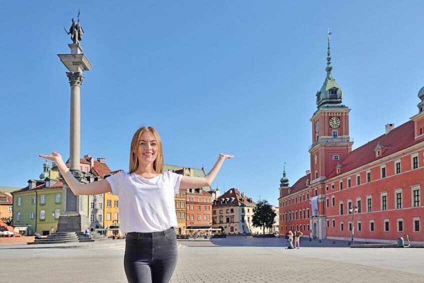 A person standing in a square with buildings and a clock tower in the background. 1