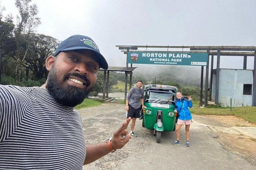 A sign for Horton Plains National Park, a green vehicle, and two people. 2