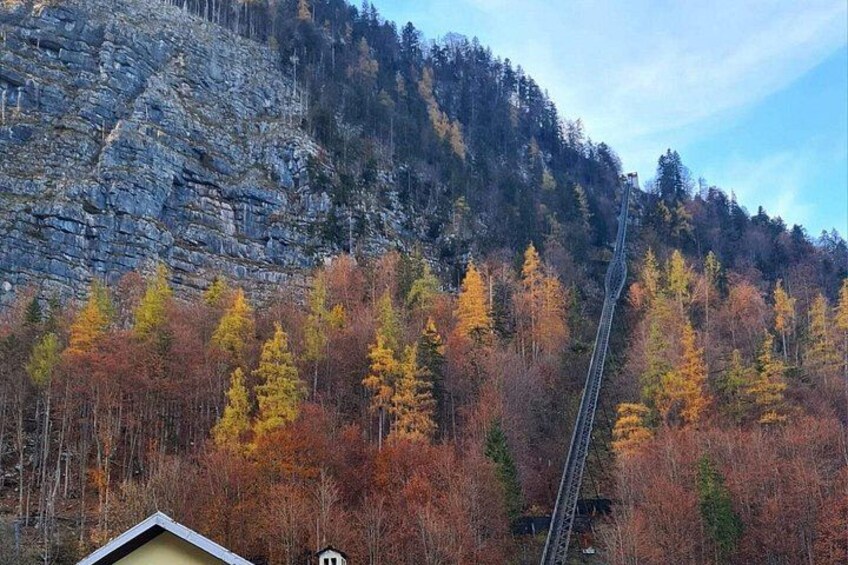 Une montagne avec une voie ferrée, des arbres aux couleurs automnales et un petit bâtiment. 4