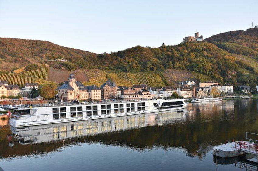 A river with a boat, buildings, and a castle on a hill. 2