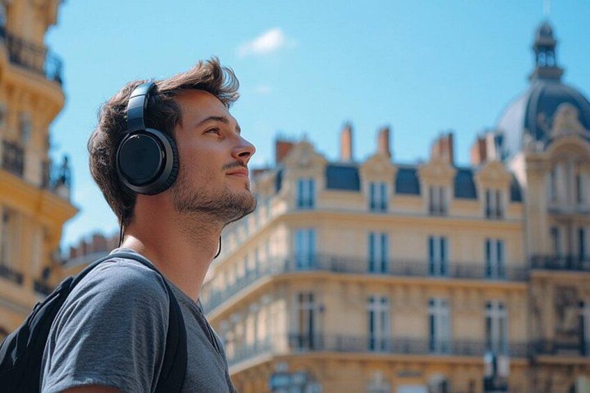 A person wearing headphones, standing in front of a historic building with multiple windows and a dome. 1