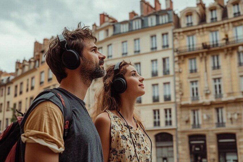 A couple wearing headphones, standing in a city with historic buildings in the background. 3