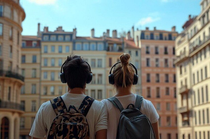 Two people walking with backpacks, facing a row of historic buildings. 5