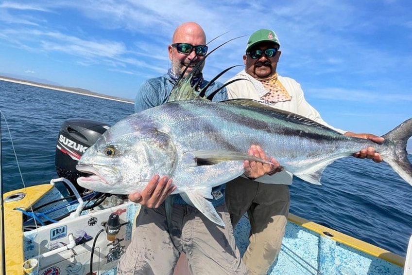 Two people holding a large fish on a boat with a Suzuki outboard motor. 2