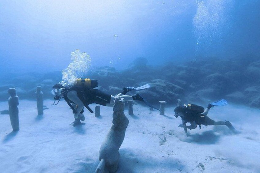 Divers underwater with a sandy seabed and some rocks. 4