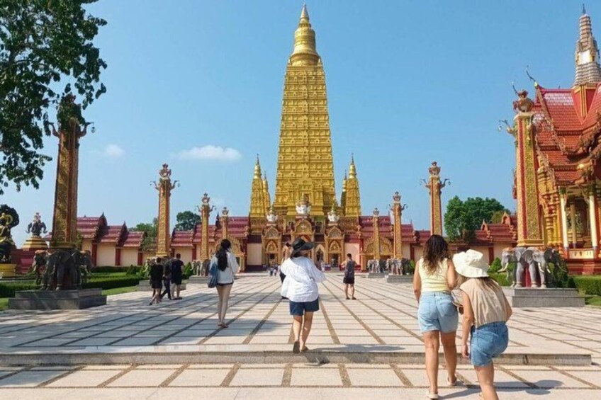 En stor gylden stupa i midten af et tempelkompleks, hvor besøgende vandrer rundt. 3