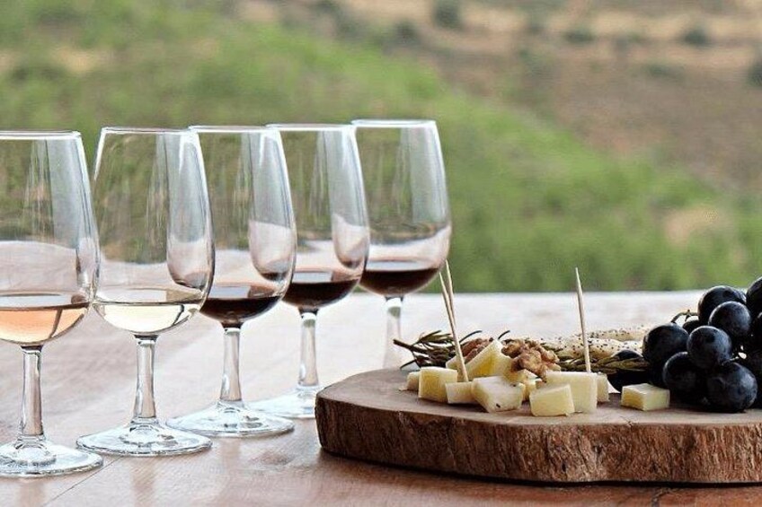A wooden table with wine glasses and a cheese board with grapes. 1