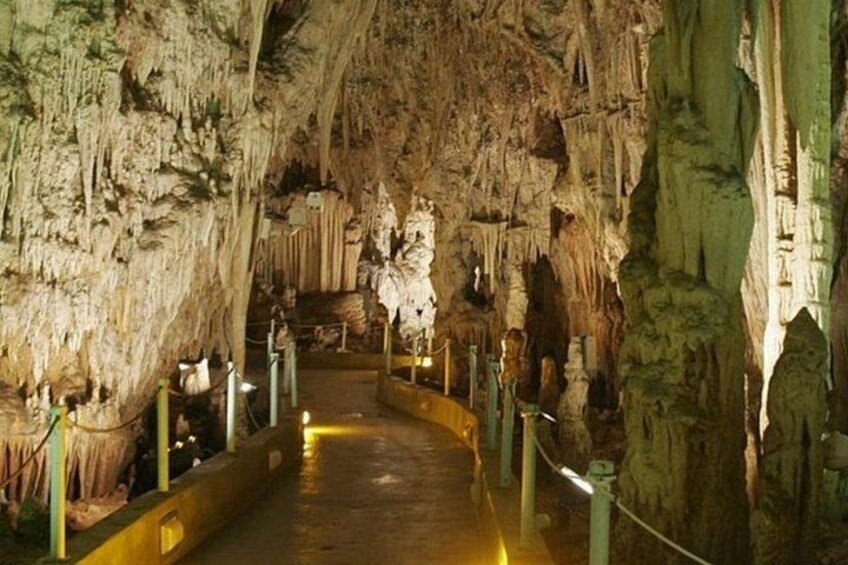 A cave with stalactites and stalagmites, a walkway, and rope barriers. 2