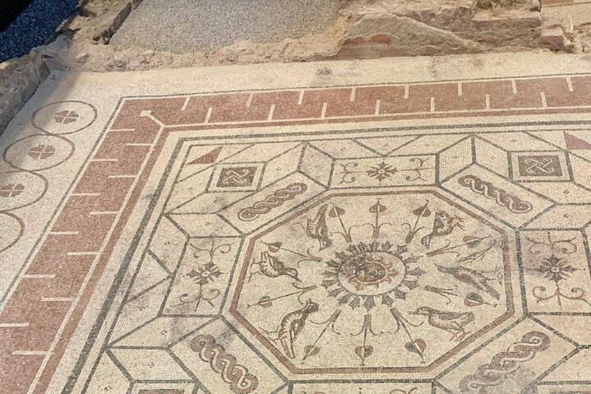 Et mosaik med geometriske mønstre og et blomsterdesign i midten. 5