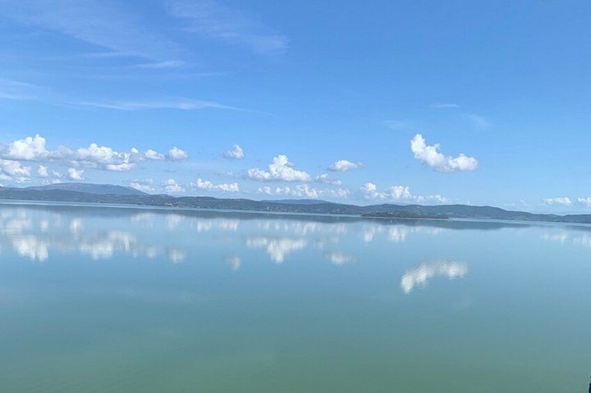Un lago tranquilo con reflejos claros del cielo y montañas distantes. 3