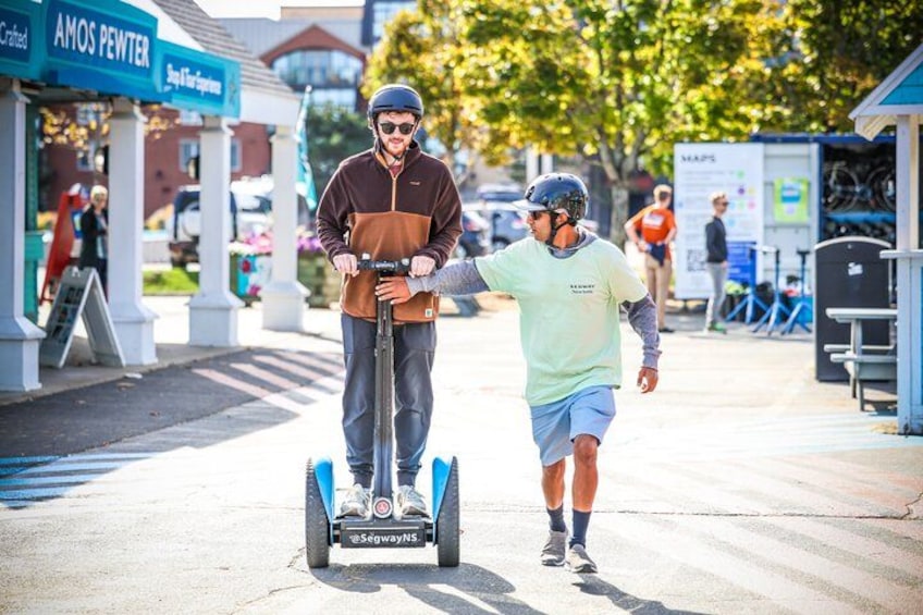 Two people on segwayboards, one riding and one walking beside. 2
