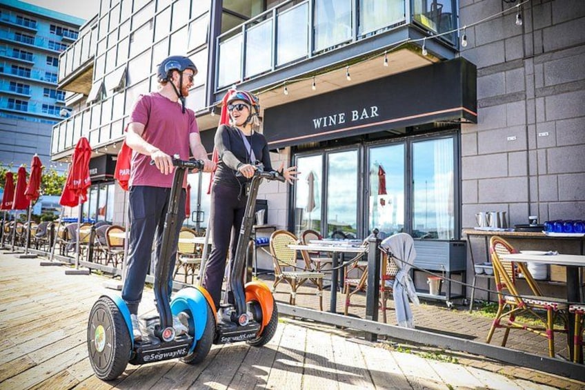 Two people on segways in front of a wine bar. 4