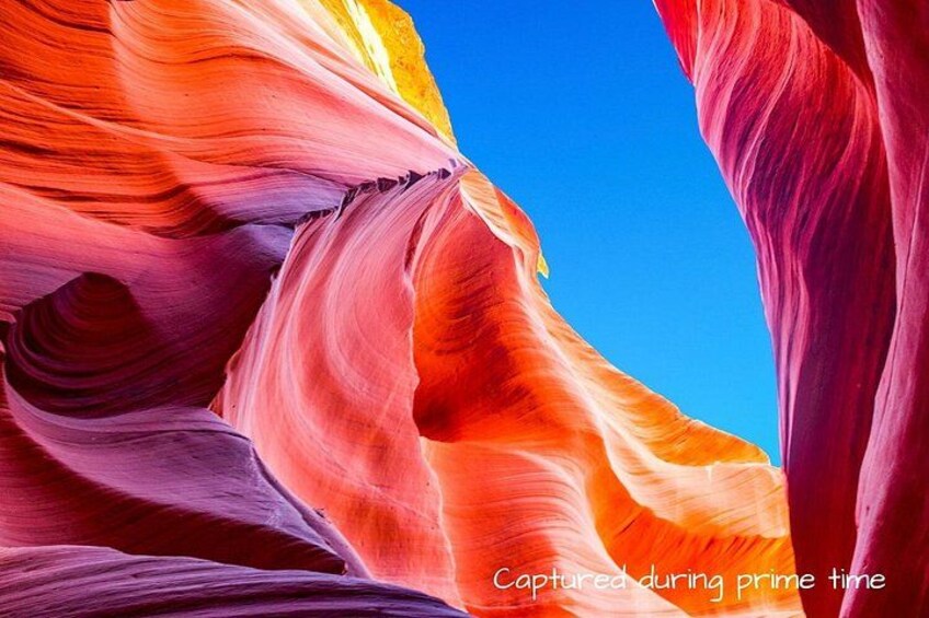 A colorful rock formation with smooth curves and a clear blue sky. 2