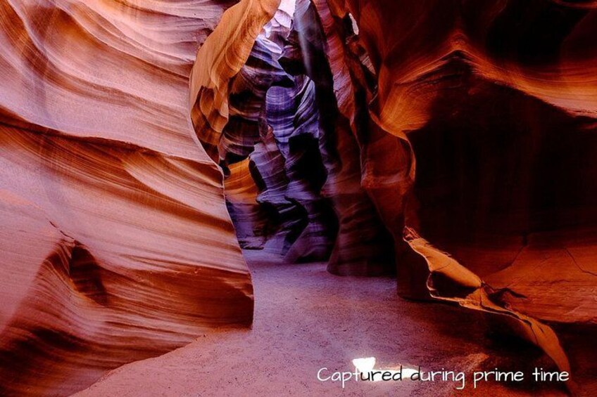 A person walking through a narrow canyon with smooth rock walls. 4