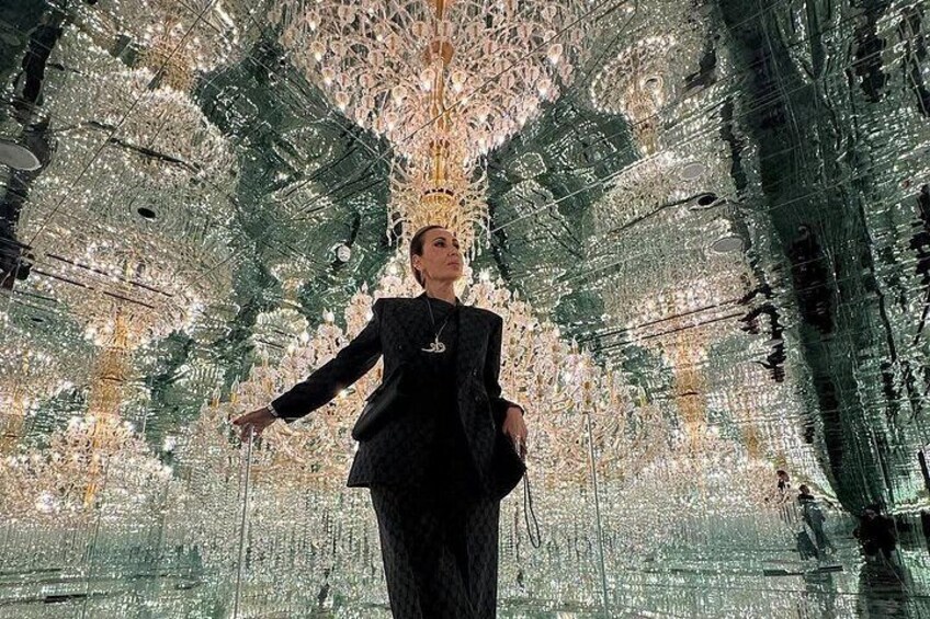 A person standing in front of a large, reflective, geometric structure. 5