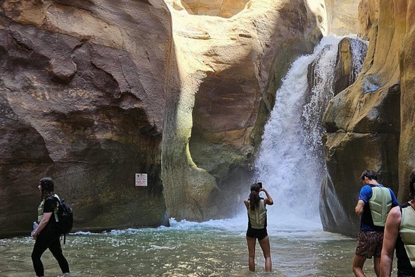 A waterfall in a canyon with people taking photos. 2