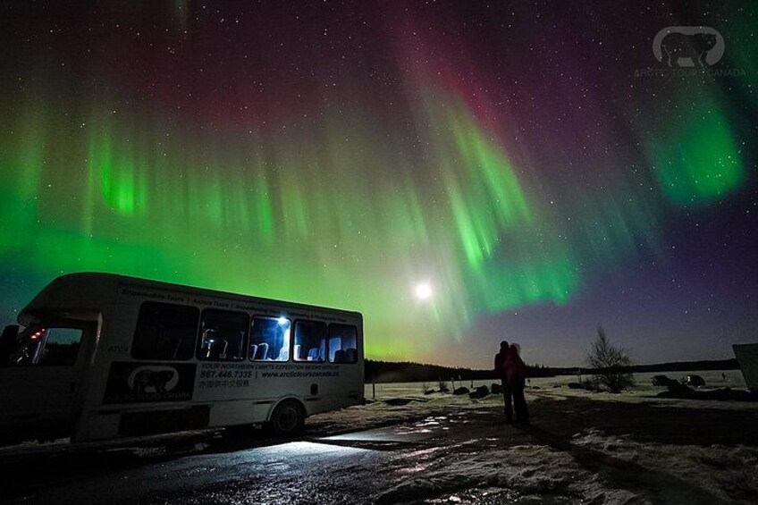 A bus parked under a night sky with the Northern Lights. 2