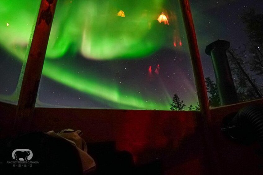 The Northern Lights (Aurora Borealis) visible through a window, with a silhouette of a bear and a chimney in the foreground. 1