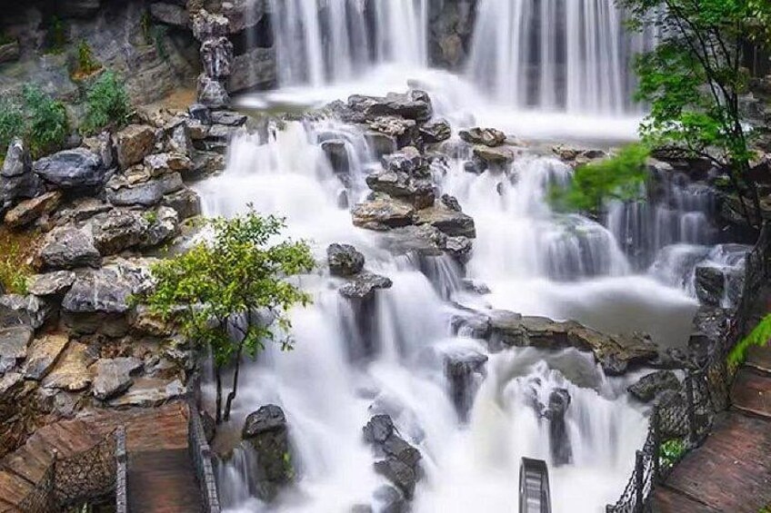 Una cascada fluye sobre rocas, rodeada de vegetación. 4