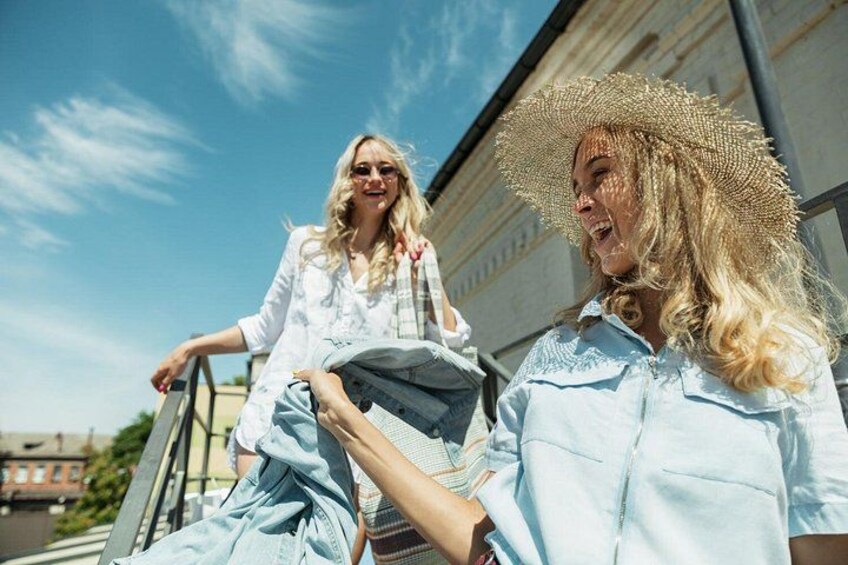 Dos personas con camisas azul claro, una llevando sombrero de paja, de pie cerca de un edificio con cielo despejado al fondo. 5