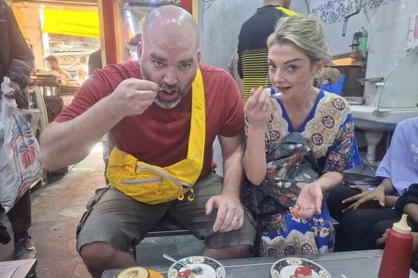 Two people sitting at a table with food, in a casual dining setting. 2