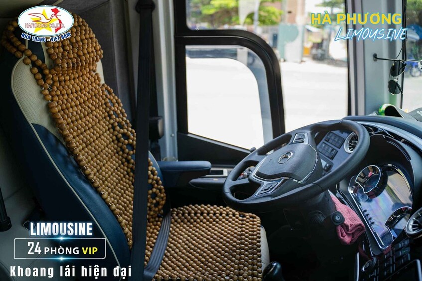 A bus interior with a steering wheel, dashboard, and seats covered with a beaded fabric. 5
