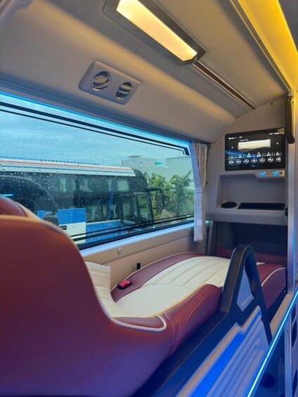 A train interior with red and beige seats, a digital display, and a window with raindrops. 5