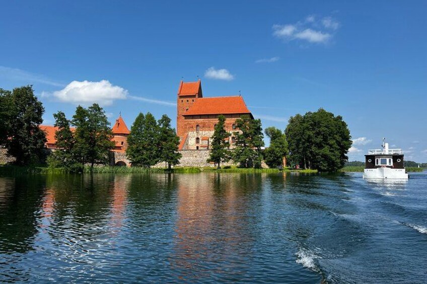 Un château aux toits rouges, un bateau sur l’eau et des arbres le long de la rive. 2