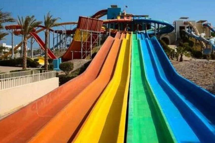 A multi-colored water slide with a high platform and palm trees in the background. 4