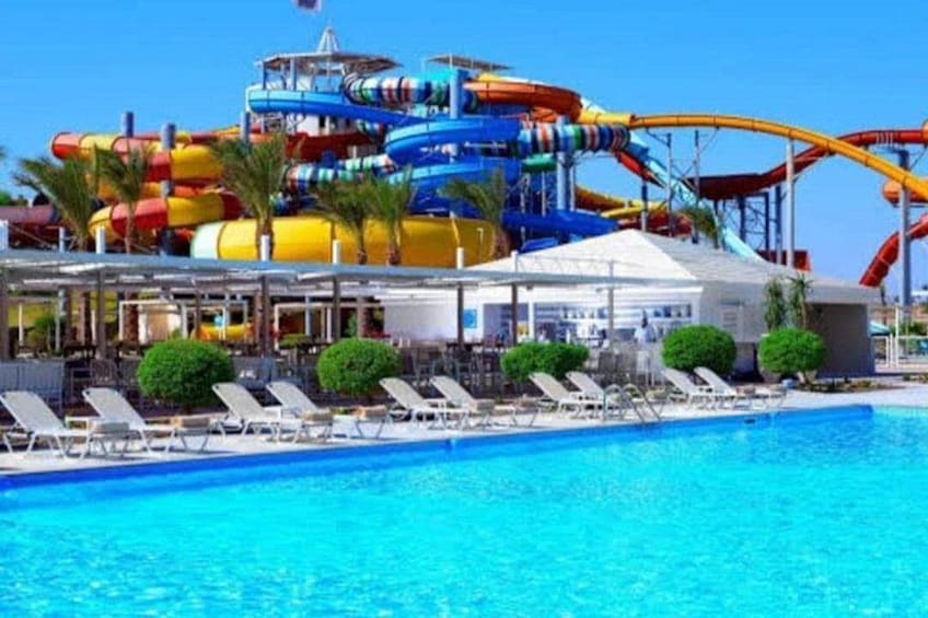 A water park with a large pool, colorful water slides, and lounge chairs. 5